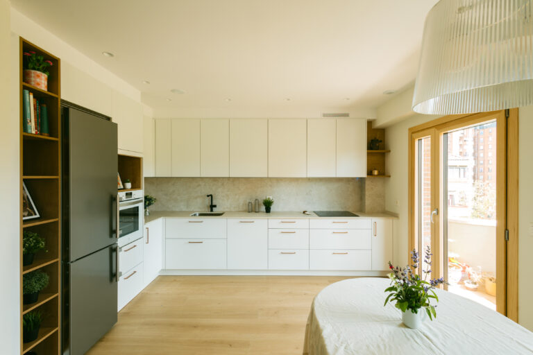 Una cocina blanca con detalles en madera y cobre